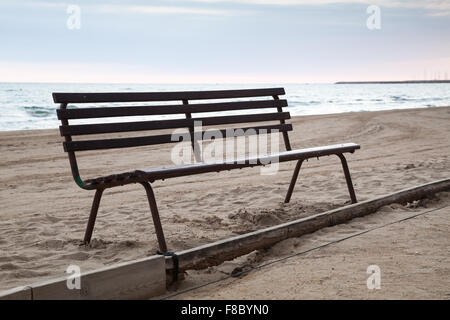 Old wooden bench stands on sandy beach, Mediterranean sea coast, Spain Stock Photo
