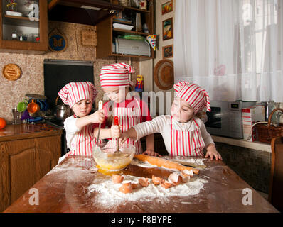 Three little chefs enjoying in the kitchen making big mess. Litt Stock Photo