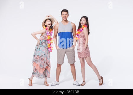 Two women in dress and sandals wearing a flower necklace and a man in casual outfits standing in between them Stock Photo