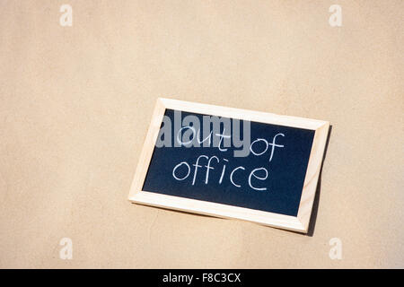 High angle copy space with word Out of Office written in a frame on sand Stock Photo