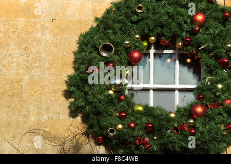 Large Christmas wreath around a window on a building. Broadway, Cotswolds. England Stock Photo