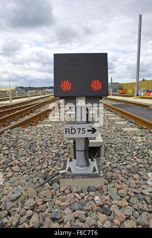 Ground Position Signal number RD 75 showing two red LED lights from the black box stood on a pillar bolted to a concrete base. Stock Photo