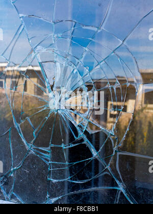 Close up view of broken glass on a window with cracks radiating out from the centre Stock Photo