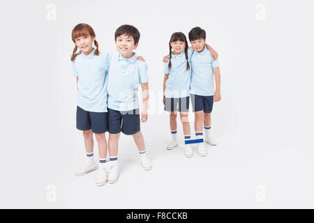 Two pairs of elementary school students with their feet tied together and their arms around each other to do three legged race Stock Photo