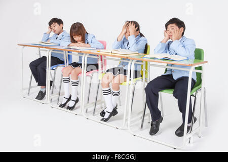 tired and bored asian elementary school boy doing homework in classroom ...