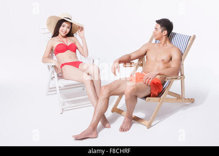 Couple in beach wear sitting on a sunbed each and relaxing Stock Photo