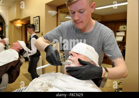 Man receiving open razorl shave from barber in Londonderry, Northern Ireland. Stock Photo