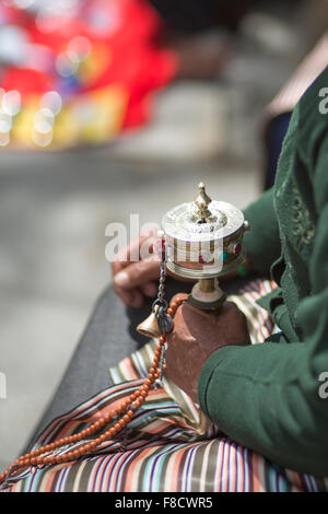 Old woman praying with prayer roll in Lhasa Stock Photo