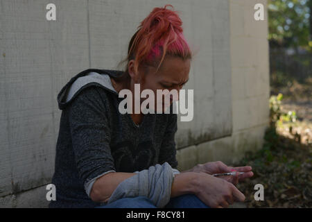 Oct. 18, 2015 - Wilmington-Cincinati, Ohio, US - Tara, a mother of five, injects heroin in her vein by an abandoned garage in an alley in the South Side neighborhood of Hamilton, Ohio, where heroin addiction is rampant, part of a growing epidemic across the U.S. Tara, who did not want her last name used, often sleeps in these alleys, which are near the home where her two young children live with their father and his mother. She has lost her three other children to the social services system. Her children's father only allows her to visit two kids before 9 a.m., when she is still sober, and whe Stock Photo