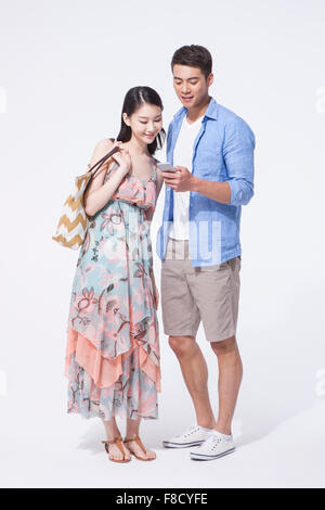 Couple in tourist fashion standing together and looking at a smartphone in man's hand Stock Photo