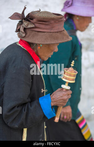 Old woman praying with prayer roll in Lhasa Stock Photo