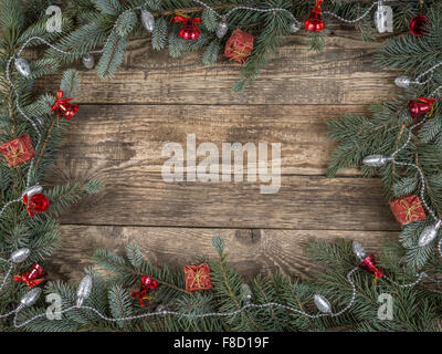 Christmas framework arranged from spruce branches and seasonal decorations placed on wooden rustic boards with copy space Stock Photo