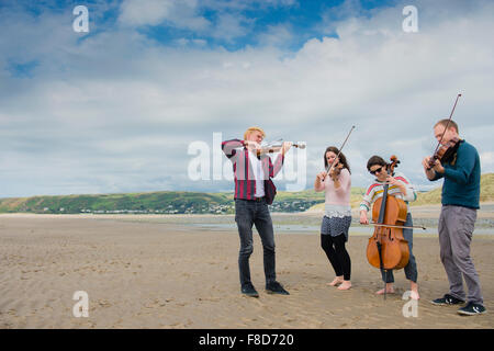 Young classical musicians: The Solem String Quartet playing their instruments outdoors on the beach  at Aberystwyth Music Fest 2015 Stock Photo