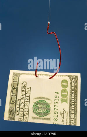 Close-up of a red fish hook with a folded one hundred dollar bill impaled on it on a blue background. Stock Photo