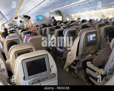 Inside an Emirates flight from Bangalore to Dubai. Passengers watching in-flight entertainment. Stock Photo