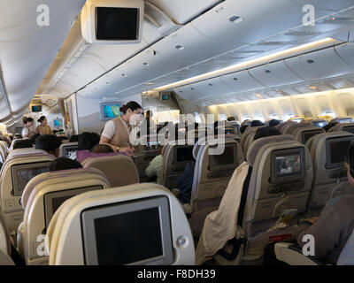 Inside an Emirates flight from Bangalore to Dubai. Passengers watching in-flight entertainment. Stock Photo