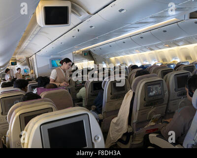 Inside an Emirates flight from Bangalore to Dubai. Passengers watching in-flight entertainment. Stock Photo