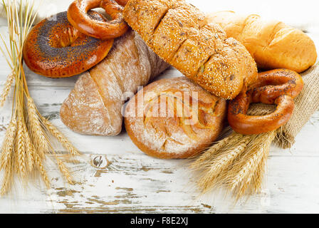 Different fresh bread and wheat on a wooden table. Stock Photo