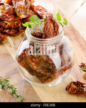 Italian sun dried tomatoes in glass jar on  wooden table. Selective focus Stock Photo