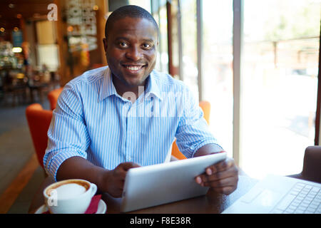Smiling man using digital tablet at cafe Stock Photo