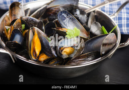 Boiled mussels in a cooking dish on a dark background. Selective focus