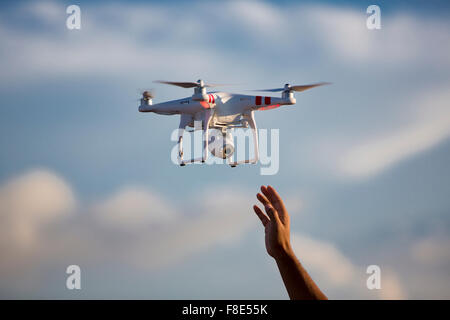 Flying radio controlled DJI Phantom quadcopter drone with video camera landing and ready to be catch by man hand. Colombia 2015 Stock Photo