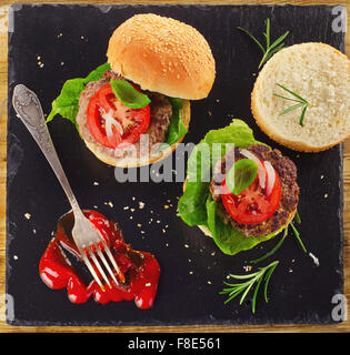 Homemade burgers with tomato sauce on dark background. Top view Stock Photo