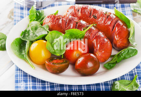 Fried sausages with fresh salad on white plate. Selective focus Stock Photo