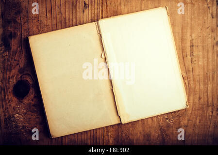 Top view of old open book with blank pages on wooden desk as copy space, retro toned image. Stock Photo