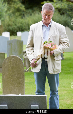 Senior Man Laying Flowers on Grave Stock Photo