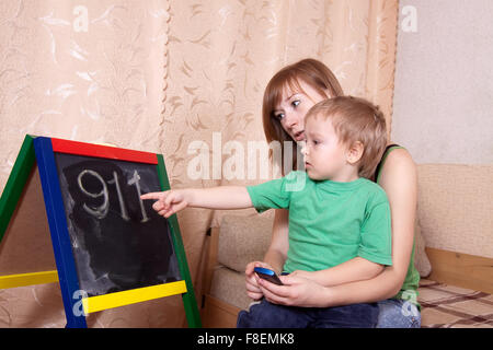 Mother teaches child to emergency phone numbers Stock Photo