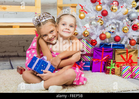 Two funny sisters four girls and six years of playing and having fun in the home New Years interior Stock Photo