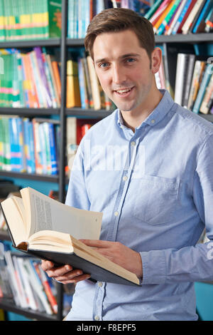 University Student Reading Textbook In Library Stock Photo