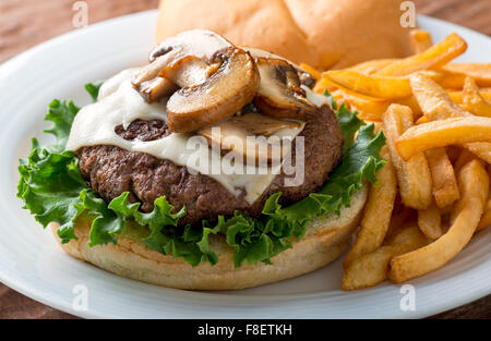 A delicious hamburger topped with swiss cheese and fried mushrooms on a kaiser. Stock Photo