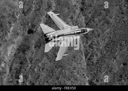 Close Up Black And White Photo Of A Royal Air Force Tornado GR4 Jet Fighter Flying At Low Level Through A Desert Valley. Stock Photo