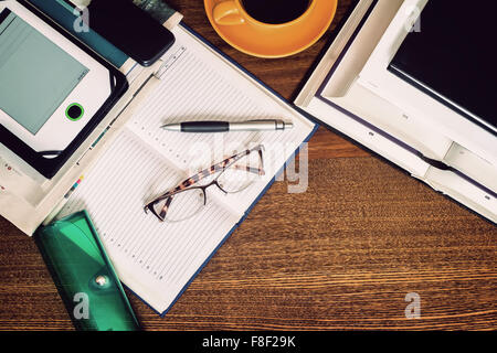 On the table lay a notebook, book , notebook, glasses, Cup of coffee. The view from the top. Stock Photo