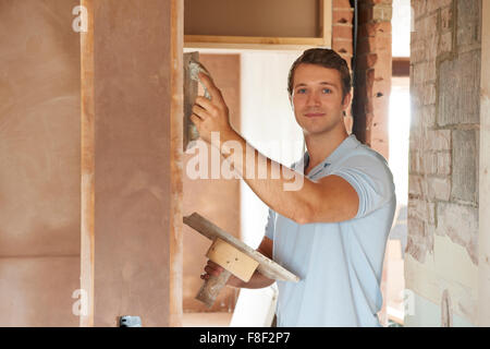 Plasterer Working On Wall On Building Site Stock Photo