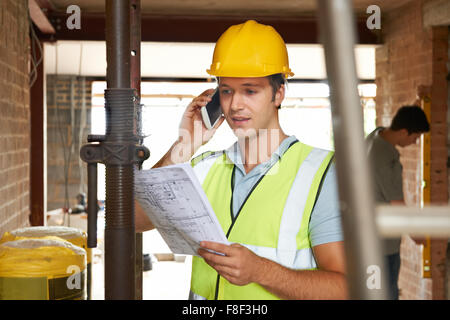 Builder On Site Using Mobile Phone Stock Photo