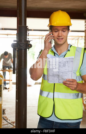 Builder On Site Using Mobile Phone Stock Photo