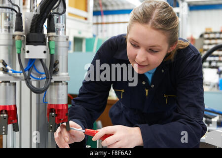 Female Apprentice Engineer Working On Machine In Factory Stock Photo