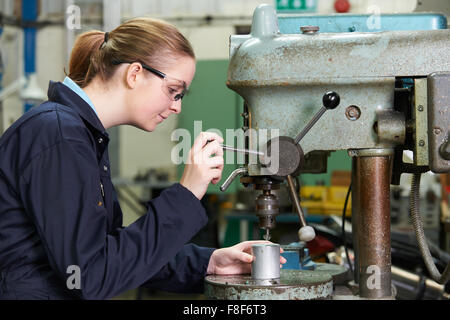 Female Apprentice Engineer Using Drill In Factory Stock Photo