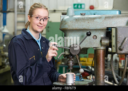 Female Apprentice Engineer Using Drill In Factory Stock Photo