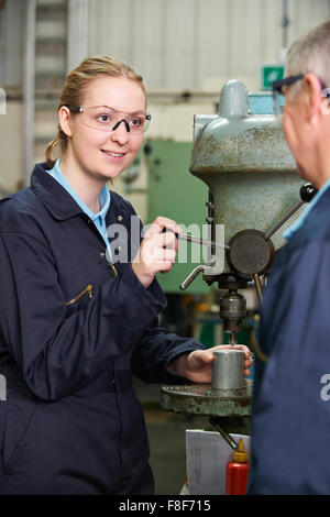 Engineer Showing Female Apprentice How To Use Drill In Factory Stock Photo