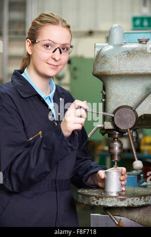 Female Apprentice Engineer Using Drill In Factory Stock Photo