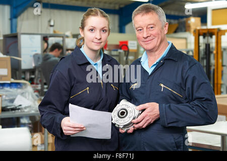 Engineer With Apprentice Looking At Component In Factory Stock Photo