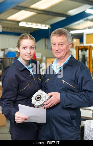 Engineer With Apprentice Looking At Component In Factory Stock Photo