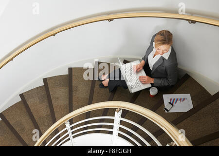 Businesswoman Sitting On Stairs Using Laptop Stock Photo