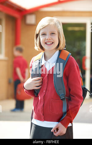 Happy girl in uniform back to school carrying books and backpack ...