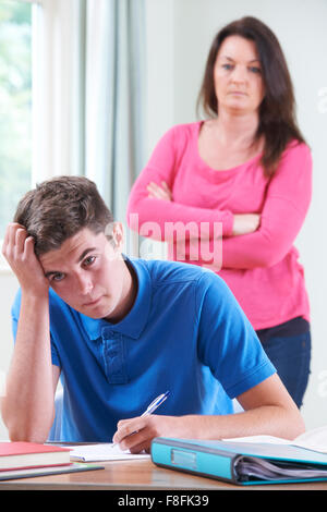 Frustrated Mother Watching Son Doing Homework Stock Photo