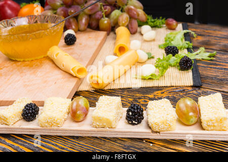 Cheese and Fruits Assortment on Cutting Board with Red, White Wine on  Wooden Background. Stock Photo by annapustynnikova